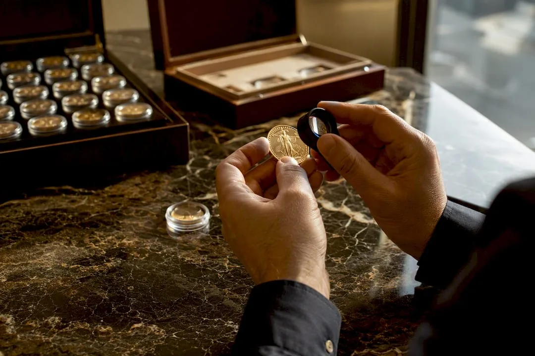 Hands inspecting gold coin with magnifier